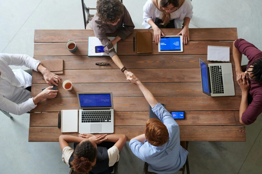 pexels-photo-3184306-3184306 Overhead view of colleagues in a work meeting using laptops and tablets, emphasizing teamwork and technology.